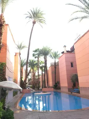 a swimming pool with palm trees and buildings at Riyad Entier Avec piscine Red Moon Kech in Marrakech