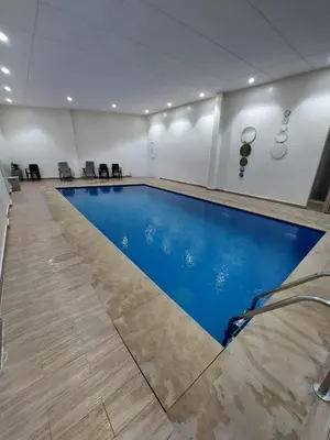 a large swimming pool in a room with blue water at Stylish Apartment with a pool in the Center of Marrakesh in Marrakech
