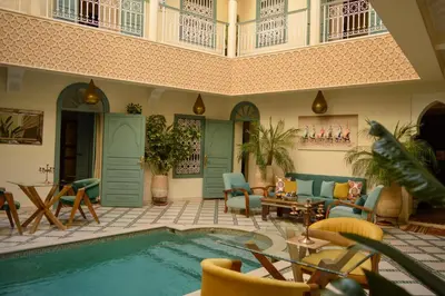 a pool in a living room with chairs and a couch at Riad Jalina in Marrakech