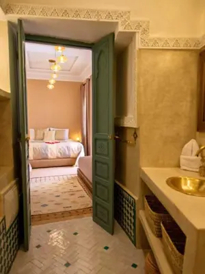 a bathroom with a sink and a room with a bed at Riad Jalina in Marrakech
