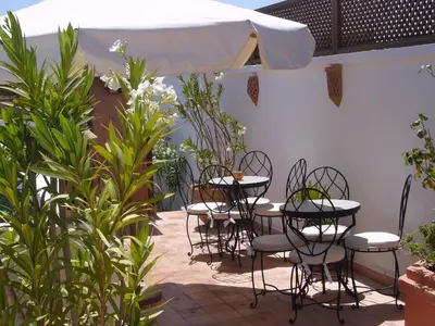 a patio with tables and chairs and a white umbrella at Riad Clémentine in Marrakech