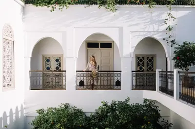 a woman standing on a balcony in a white building at Riad Clémentine in Marrakech