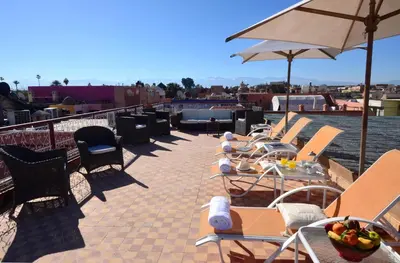a row of tables and chairs and an umbrella on a roof at Riad Manissa in Marrakech
