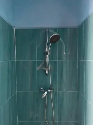a shower with a shower head in a green bathroom at Dxb Riad 4 suites in Marrakech