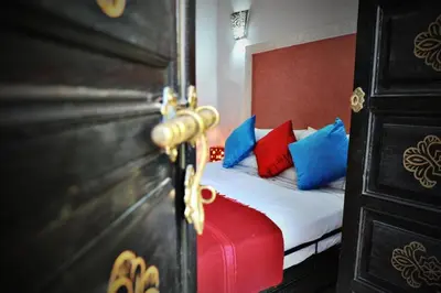 a bedroom with a bed with blue and red pillows at Dar Nossa in Marrakech