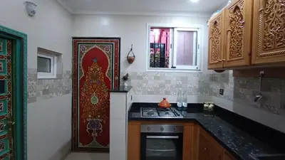 a kitchen with a stove and a red door at Riad à Marrakech dans la Résidence Touristique Al Qaria Assiyahia in Marrakech