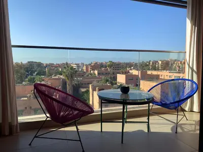 two chairs and a table in front of a window at Luxueux Appart Hivernage avec vue sur L''Atlas in Marrakech