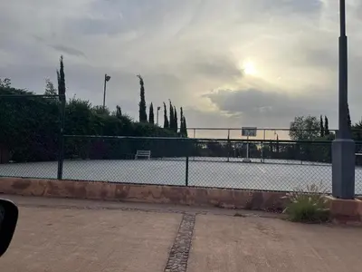 a tennis court with a fence and trees in the background at appartement dans Jardin de l'atlas in Marrakech