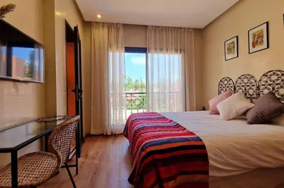 a bedroom with a bed and a desk and a window at Appartement raffiné idéalement situé avec piscine in Marrakech