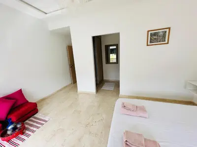 a white room with a bed and a red couch at Family Palms Luxe Villa Marrakech with Private Pool in Marrakech