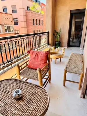 a balcony with a table and chairs and a red pillow at Appartement centre Guéliz avec terrasse spacieuse in Marrakech