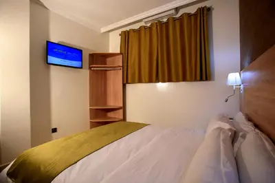 a hotel room with a bed and a flat screen tv at Hotel Ichbilia فندق اشبيلية in Marrakech