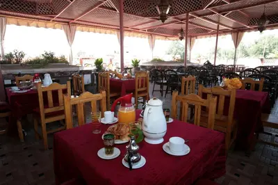 a table in a restaurant with red table cloth at Hotel Ichbilia فندق اشبيلية in Marrakech