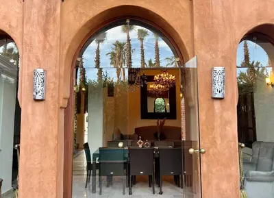 a dining room with a table and some palm trees at The Majestic Marrakesh Villa 2 in Marrakech
