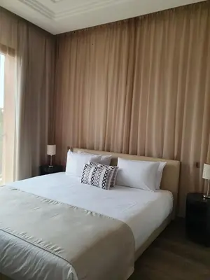 a bedroom with a large white bed with two lamps at Vizir Center Appartements in Dar Caïd Layadi