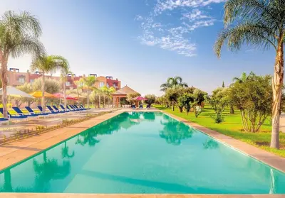 a large swimming pool with chairs and palm trees at Vizir Center Appartements in Dar Caïd Layadi
