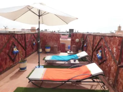 two chairs and an umbrella on a balcony at Riad BAHIA in Marrakech