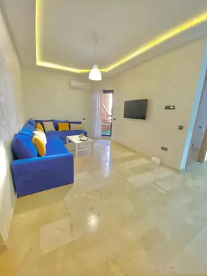 a living room with a blue couch and a tv at Appartement avec piscine en face à la gare gueliz in Marrakech