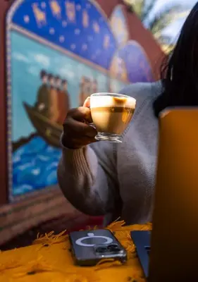 a person holding a cup of coffee on a table at Le Palais Averroes - Adults Only in Marrakech
