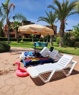 two lawn chairs and an umbrella and a toy swan at Tres joli Apparemment atlas golf rosort by marwa € ilyes in Marrakech