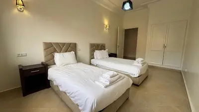 two beds in a hotel room with white sheets at Magnifique appartement Marrakech in Marrakech
