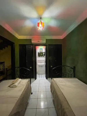 a bedroom with two beds and a bathroom with a tub at Riad Majestic Marrakech in Marrakech