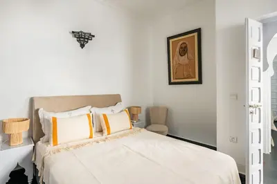 a white bedroom with a bed with yellow and white pillows at Riad l'Empire in Marrakech