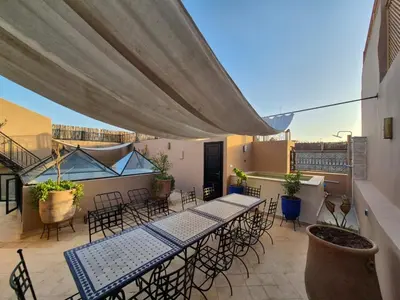 a patio with tables and chairs on a balcony at Riad l'Empire in Marrakech