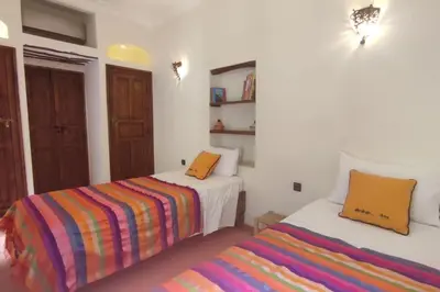 a bedroom with two beds and a colorful striped blanket at RIAD PRIVATISÉ 3 Chambres 6 Personnes Place Jemma El Fna in Marrakech