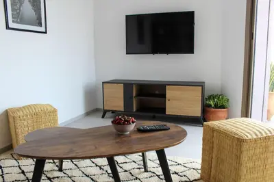 a living room with a table and a tv at STUDIO MODERNE PROCHE MACDO RTE CASA in Marrakech