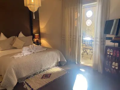a bedroom with a bed and a window with a chair at Bel appartement en centre-ville avec piscine in Marrakech