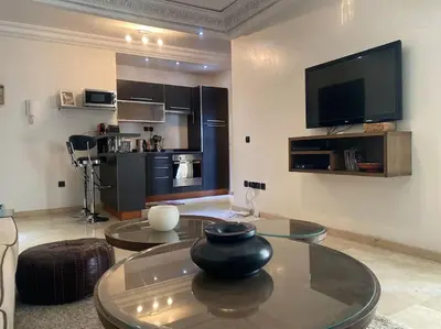 a living room with a table and a flat screen tv at Bel appartement en centre-ville avec piscine in Marrakech