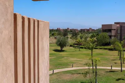 a concrete wall with a field and buildings in the background at BEL APPART FONCTIONNEL PRESTIGIA GOLF MARRAKECH in Marrakech