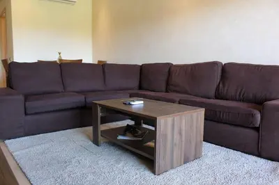 a brown couch with a coffee table in a living room at BEL APPART FONCTIONNEL PRESTIGIA GOLF MARRAKECH in Marrakech