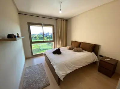 a bedroom with a bed with a black cat on it at BEL APPART FONCTIONNEL PRESTIGIA GOLF MARRAKECH in Marrakech