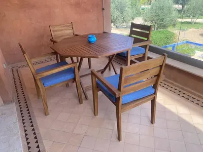 a wooden table and chairs on a porch with a table and chairs at Appartement Privé 1 Chambre Vizir Center Marrakech in Marrakech