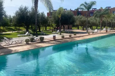 a large swimming pool in a park with palm trees at Appartement Privé 1 Chambre Vizir Center Marrakech in Marrakech