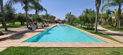 a swimming pool in a park with palm trees at Appartement Privé 1 Chambre Vizir Center Marrakech in Marrakech