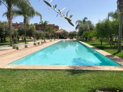 a swimming pool in a yard with palm trees at Appartement Privé 1 Chambre Vizir Center Marrakech in Marrakech
