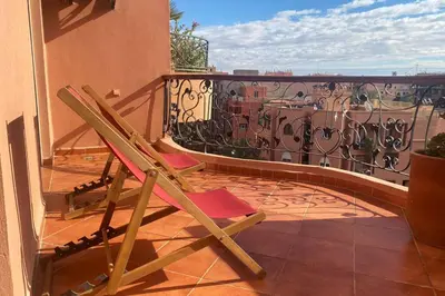 a wooden chair sitting on a balcony with a fence at Sunny terrace & comfy beds in Marrakech in Marrakech