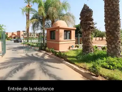 a small building on the side of a street with palm trees at Marrakech Atlas Golf Resort appartement 2 chambres,Piscines in Marrakech