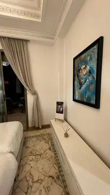 a bedroom with a painting of a man on the wall at Très joli Appart à la palmeraie coup de cœur in Marrakech