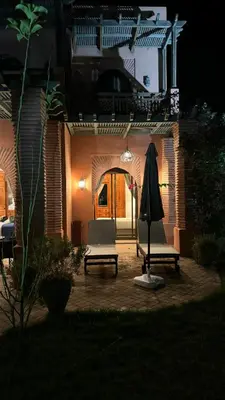 a patio with two chairs and an umbrella at night at Très joli Appart à la palmeraie coup de cœur in Marrakech