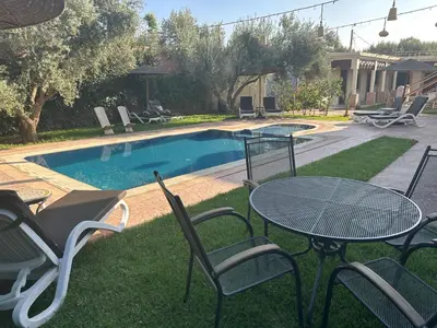 a table and chairs next to a swimming pool at Oasis Merasi Marrakech in Marrakech