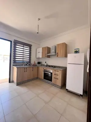 a kitchen with wooden cabinets and a white refrigerator at NOUR appartement in Marrakech