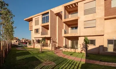 a building with a grass yard in front of it at Magnifique appartement Les perles de marrakech lux avec 2 piscines in Marrakech