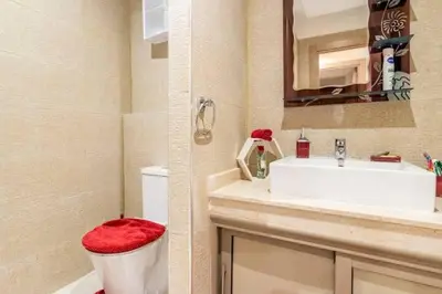 a bathroom with a sink and a toilet with a red seat at Magnifique appartement Les perles de marrakech lux avec 2 piscines in Marrakech