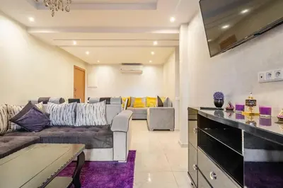 a living room with a couch and a table at Magnifique appartement Les perles de marrakech lux avec 2 piscines in Marrakech