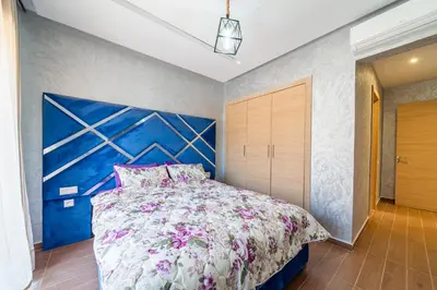 a bedroom with a large bed with a blue wall at Résidence Coralia les orangers in Marrakech