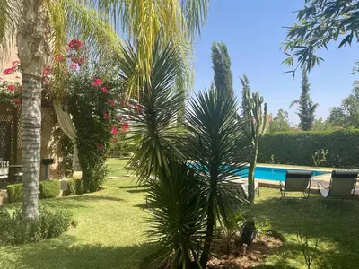 a garden with a swimming pool and palm trees at Rita House - Le Petit Paradis sur Terre in Douar Caïd Layadi